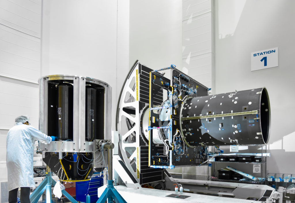 This image shows a Maxar technician in a lab coat working on part of the Psyche spacecraft.