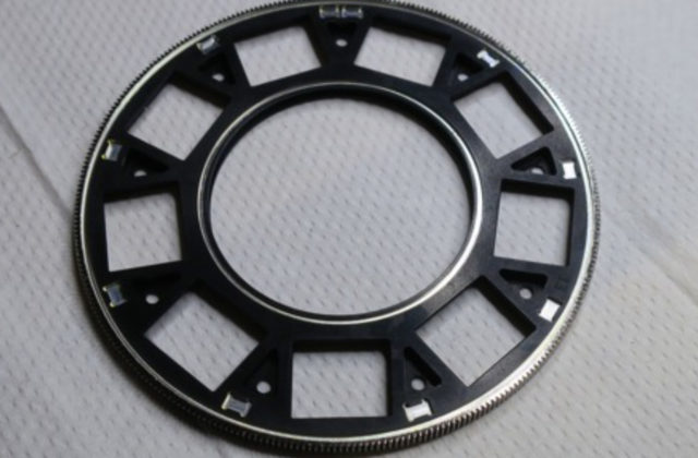 This image shows a black circular wheel with rectangular holes cut out and many tiny "teeth" along the outer rim.