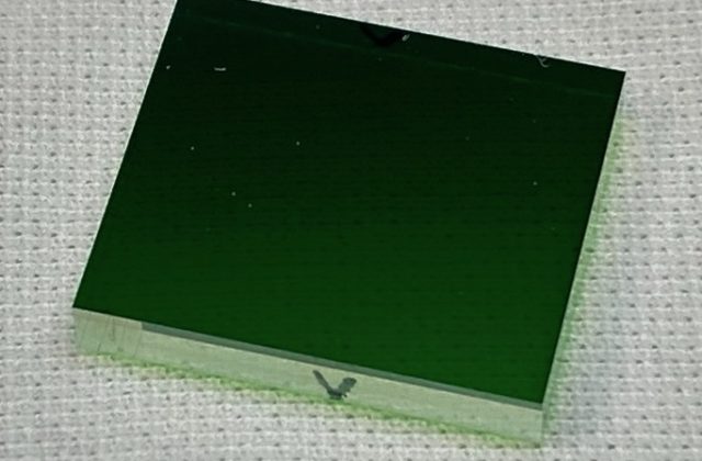 Small green glass rectangle on white woven material.