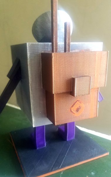 A square silver cube figure with purple rectangular arms and rectangular body stands on a table looking out a window. It has a satellite dish as a hat and wears a bronze painted cube backpack. There is a lens flare casting light into the room onto the figure's face as it looks at a tree in the distance.