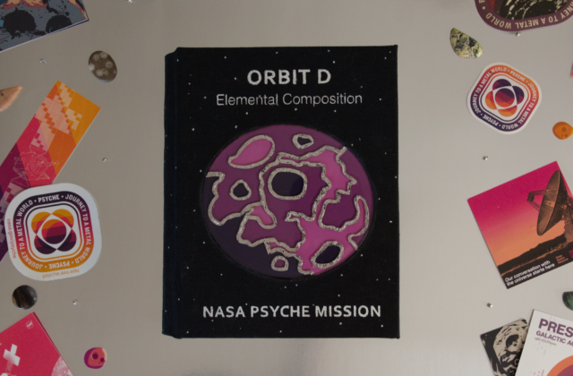 Psyche Mission Orbit D Notebook is the last in the series. The cover is a faux stained glass made of acrylic, and constructed with solder. The pattern represents elemental maps that assign an element a color and map it across the surface to see the element distribution. LED’s light up from behind giving a gemlike effect for the final touch.