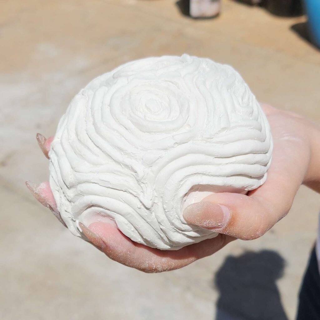 Psyche's Touch is a small plaster asteroid fits in your hand. Raised ripples radiate out like waves in water from the hand print underneath. This sculpture captures a moment of touch echoing outward, like a quiet ripple through space.