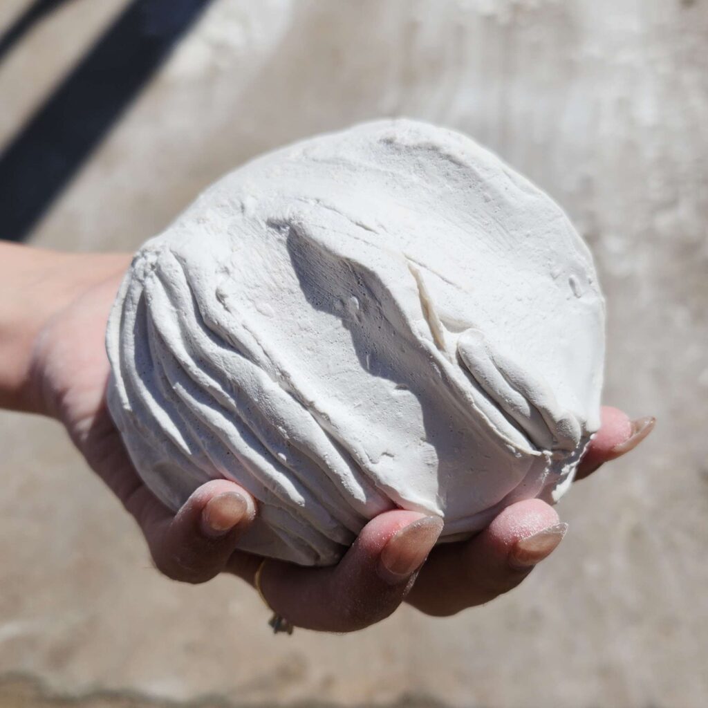 Psyche's Touch is a small plaster asteroid fits in your hand. Raised ripples radiate out like waves in water from the hand print underneath. This sculpture captures a moment of touch echoing outward, like a quiet ripple through space.