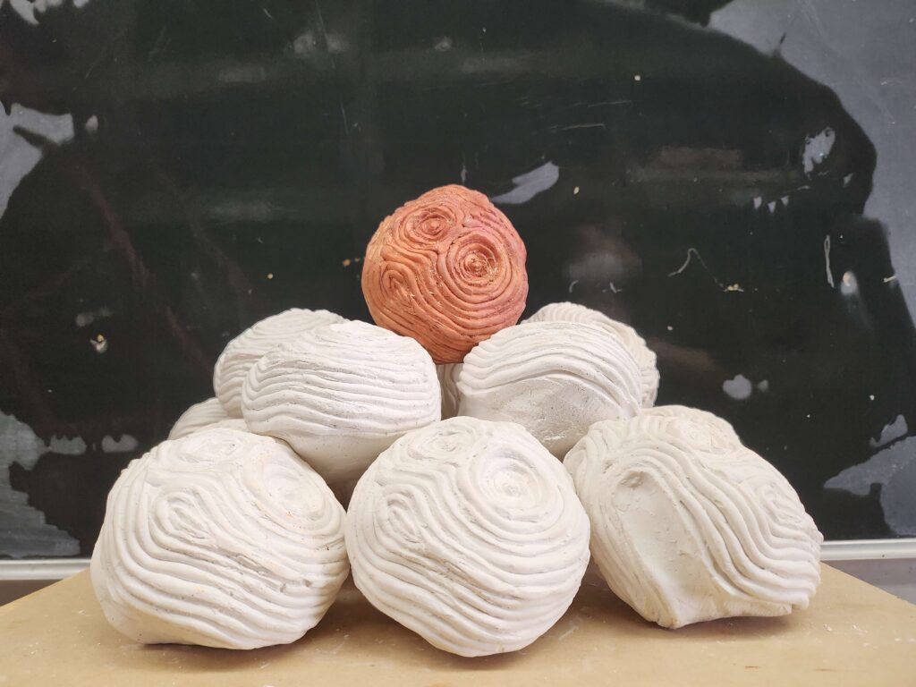 Psyche's Touch is a small plaster asteroid fits in your hand. Raised ripples radiate out like waves in water from the hand print underneath. This sculpture captures a moment of touch echoing outward, like a quiet ripple through space.