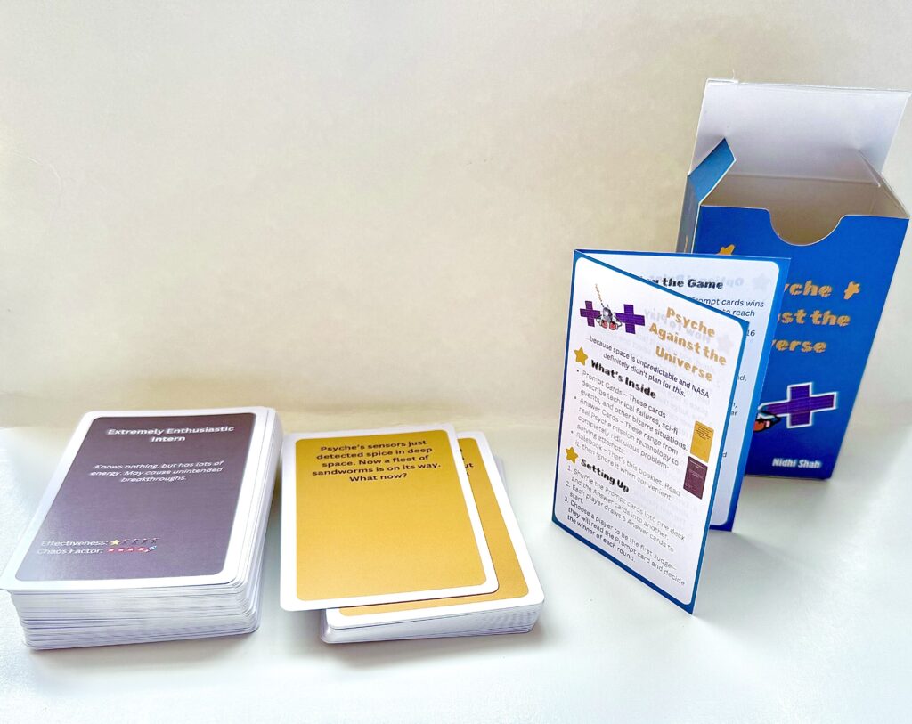 The card game consists of a blue box decorated with cartoonish designs including the spacecraft with punching mitts. Inside there are yellow prompt cards and brown answer cards with a title and funny description. Answer cards also have rankings for their effectiveness and chaos factor. There is also a rulebook which describes the contents and additional rules to add chaos to the game.
